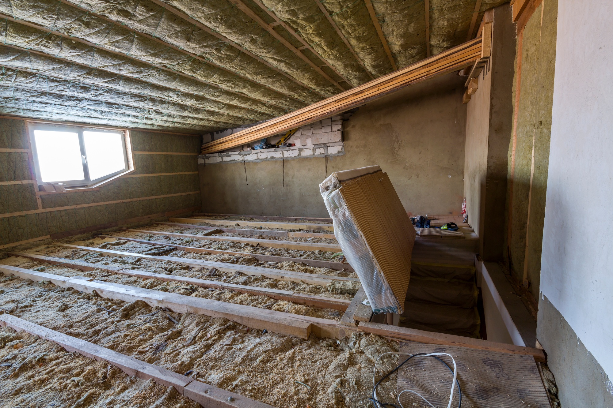 House attic under construction. Mansard walls and ceiling insulation with rock wool.